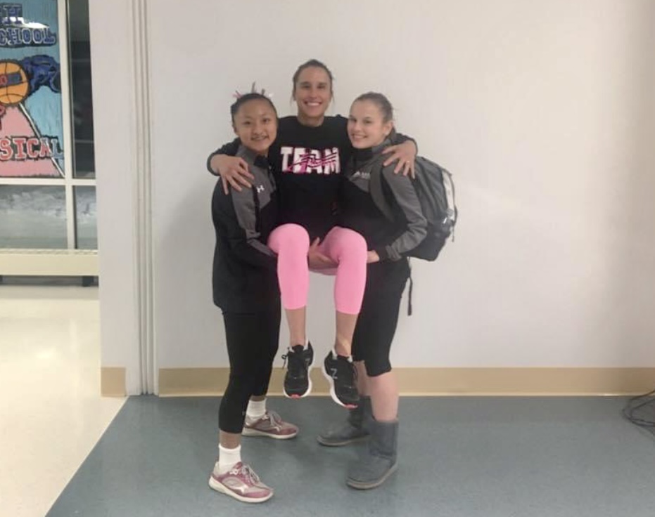 two gymnasts hold up a third